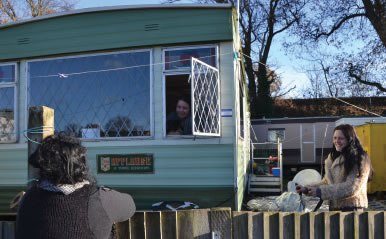 Three women having a conversation outside and from within a trailer