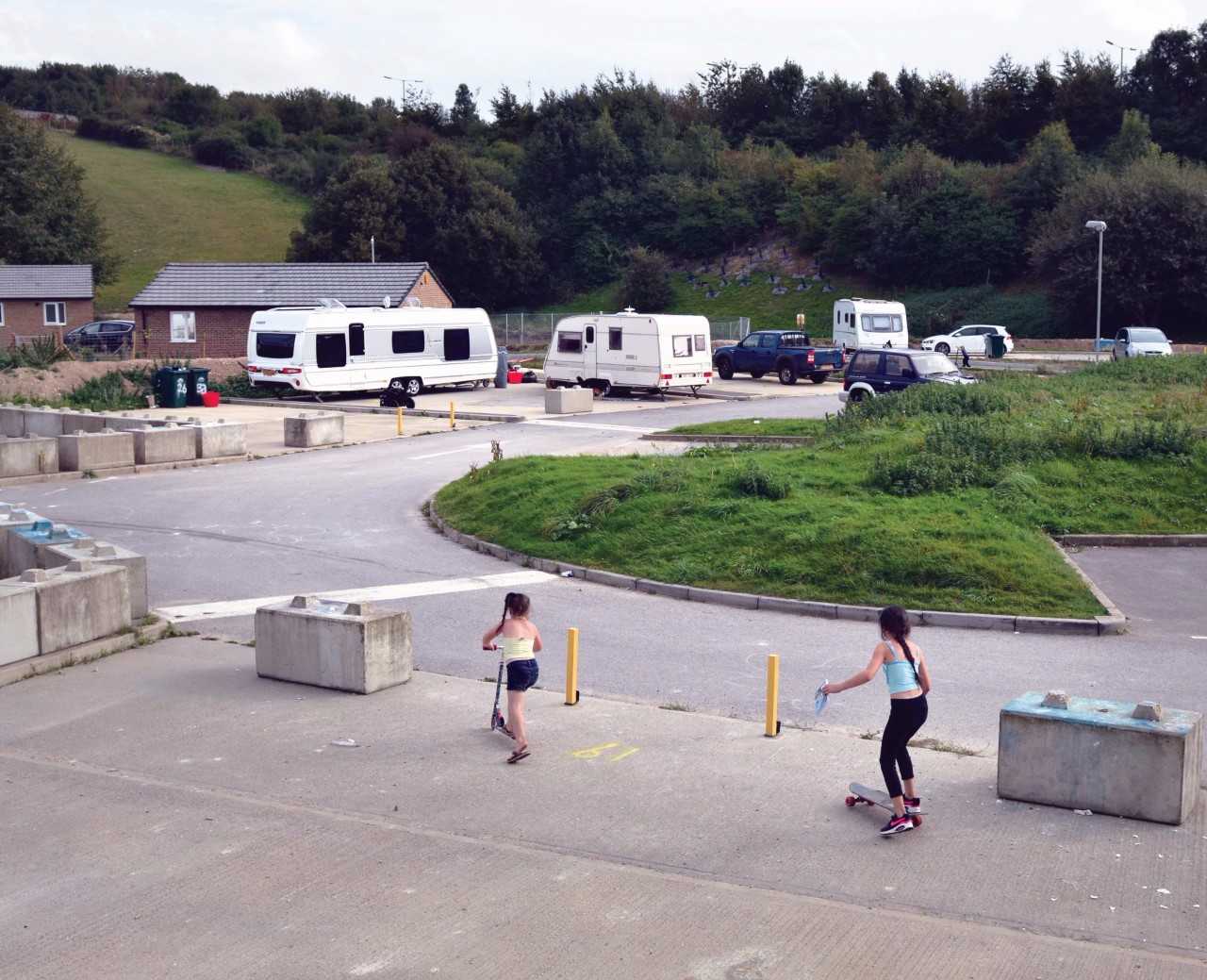 Picture of children playing on a site on scooters and skateboard