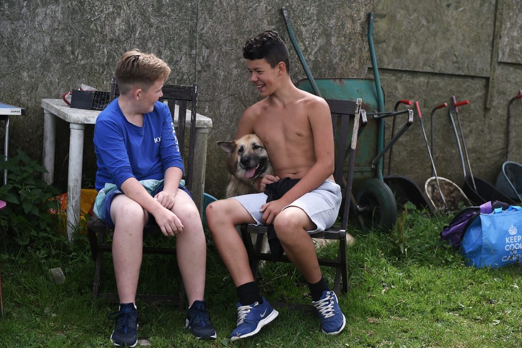 Picture of two boys sitting down with a dog