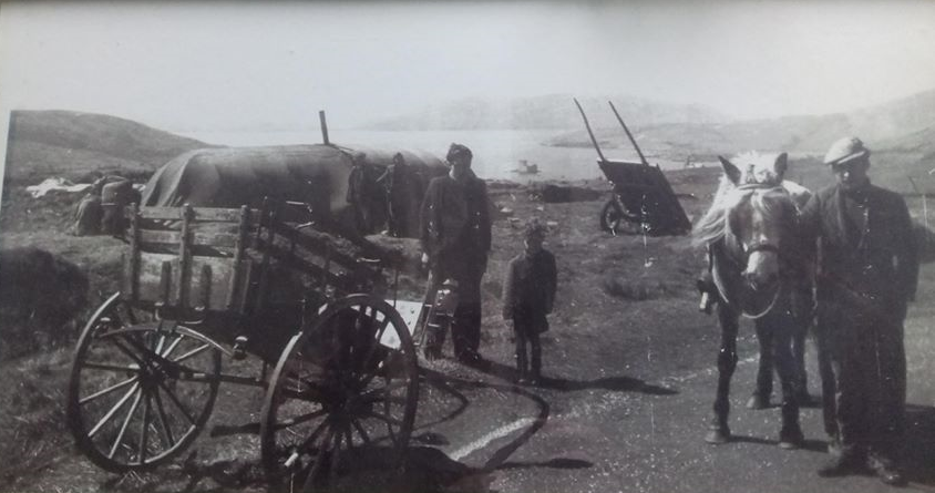 Black and white picture of men, horses and carts by the sea