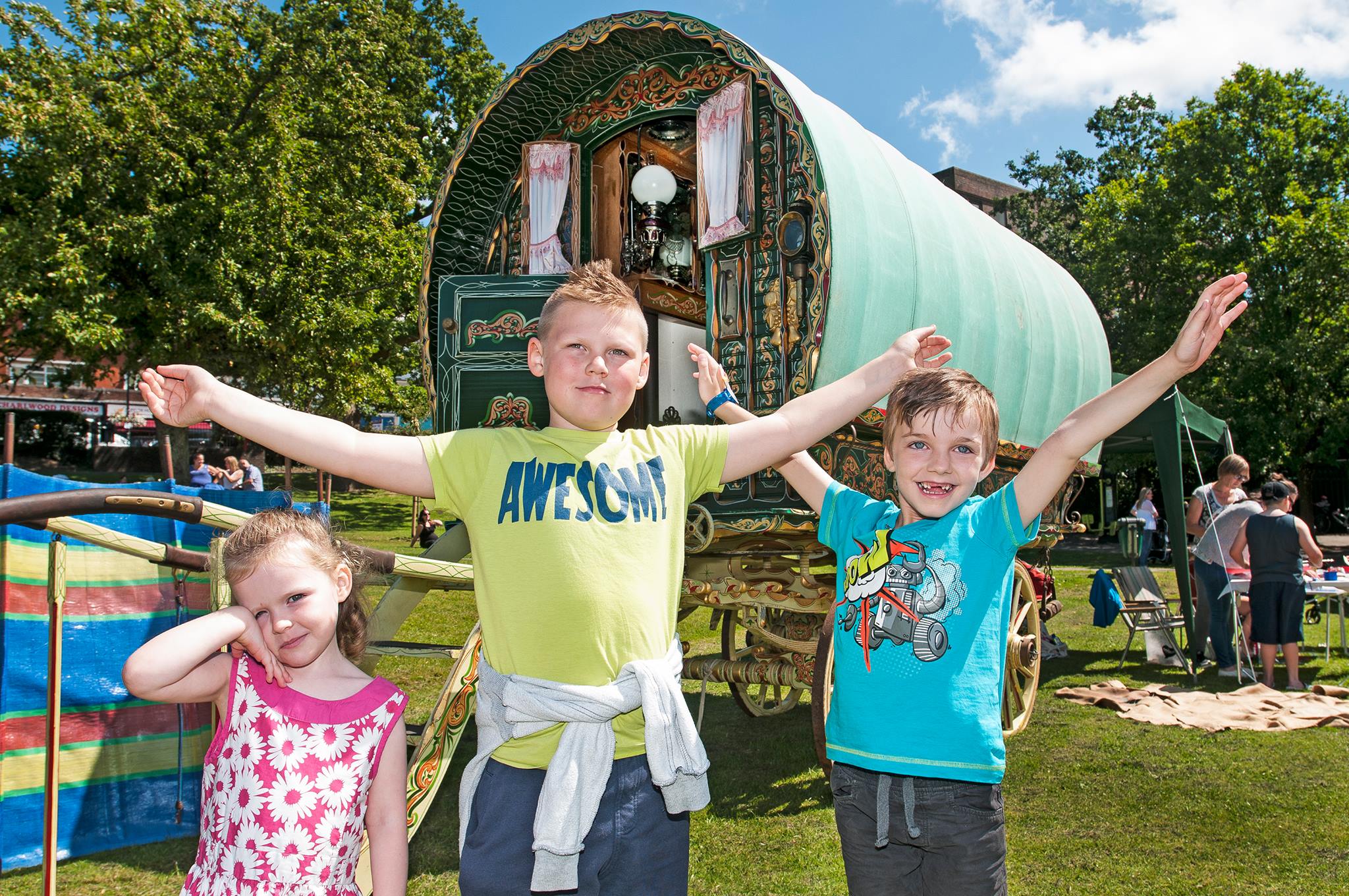 Picture of three children stood in front of a traditional Gypsy wagon