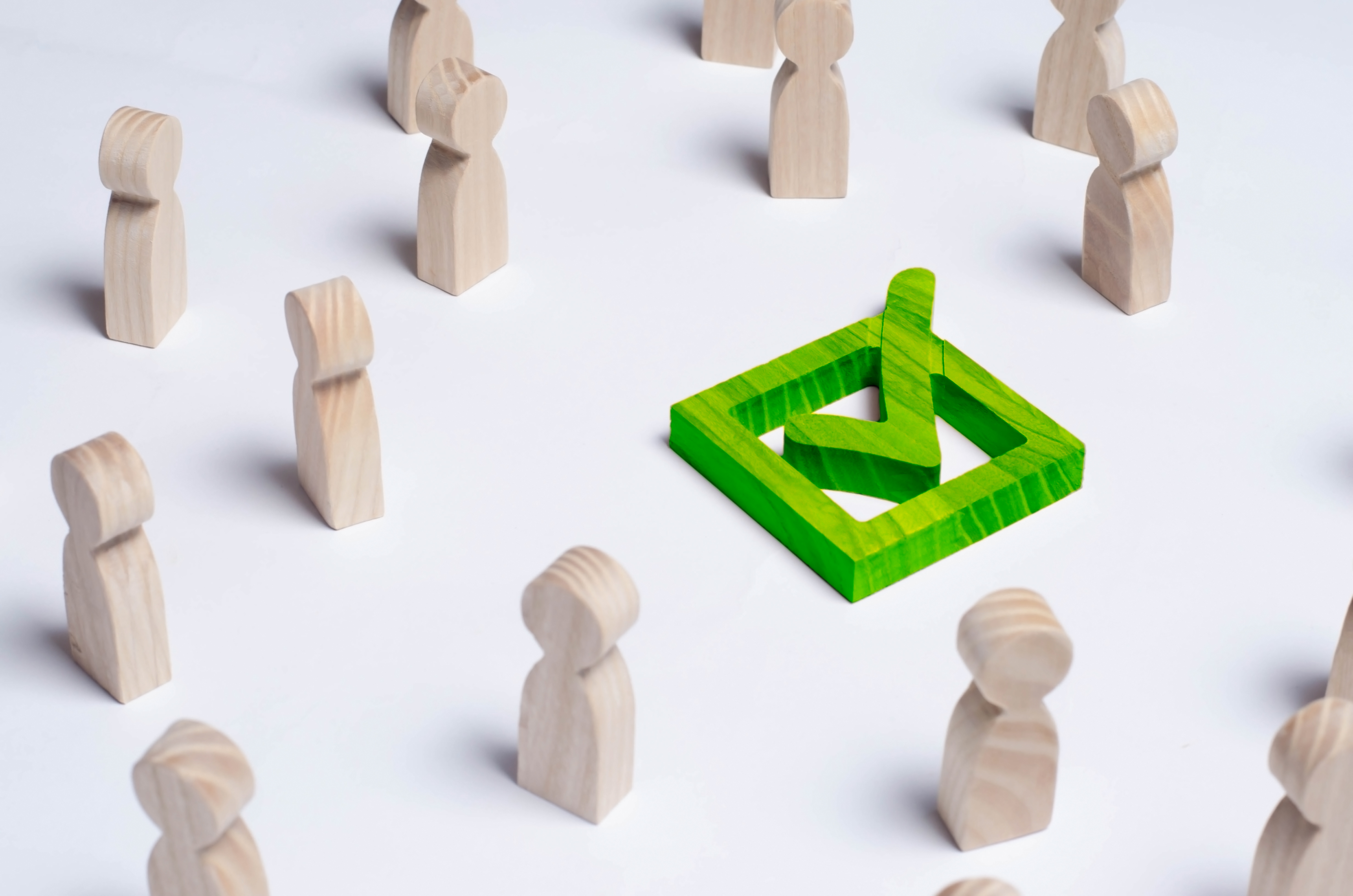 Picture of green tick in box surrounded by wooden people figures