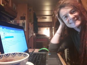 A woman leaning her head in her hand sitting next to her laptop