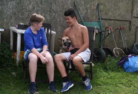Picture of two boys sitting down with a dog