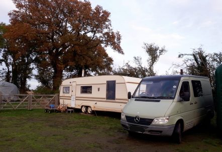 A mobile home with a transit van on a green field