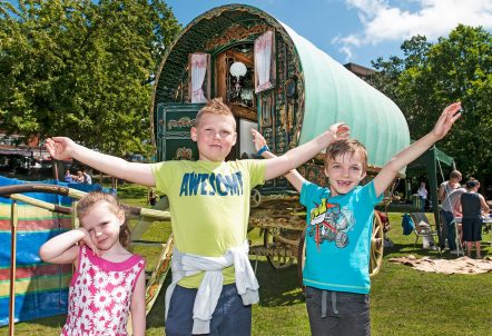 Picture of three children stood in front of a traditional Gypsy wagon