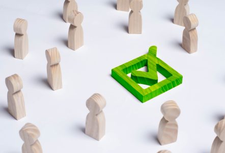 Picture of green tick in box surrounded by wooden people figures